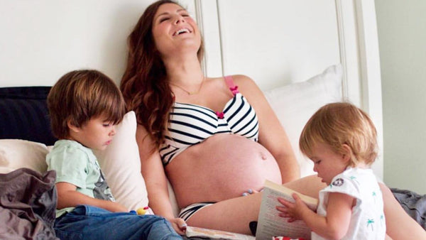 pregnant mom in maternity matching lingerie set on bed with her kids