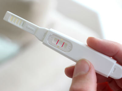 right hand holding a positive pregnancy test kit