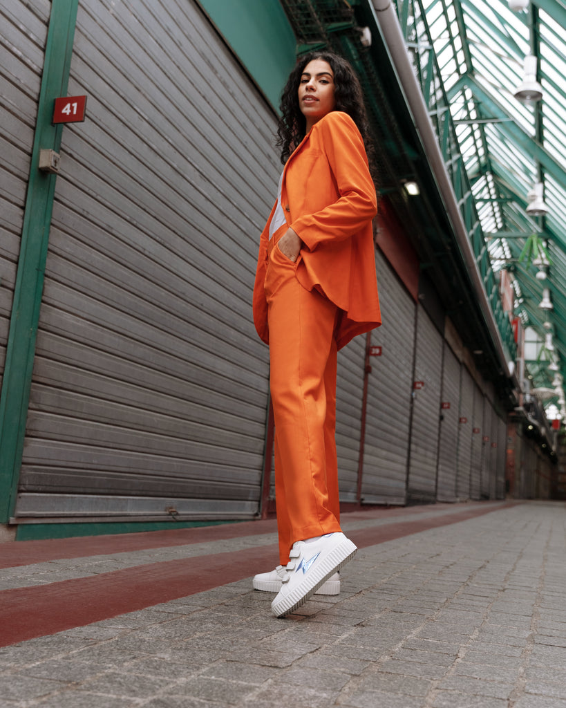 Tailleur coloré en orange pour un look funky, avec des baskets éclair Vanessa Wu en blanc et bleu à scratchs