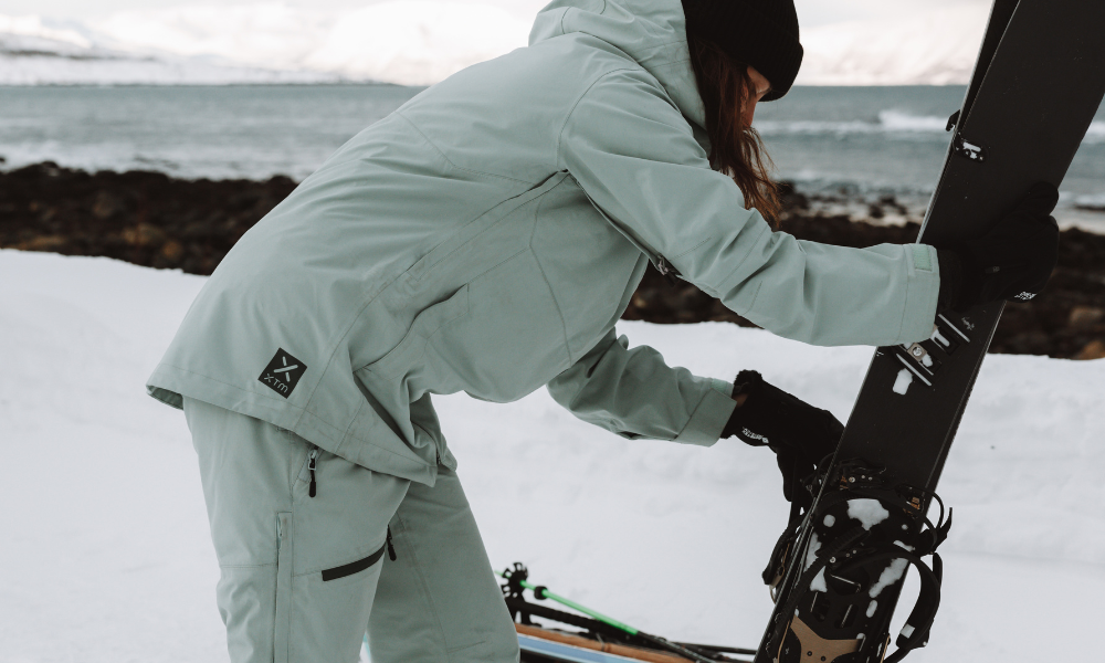 Female in green matching outerwear holding splitboard