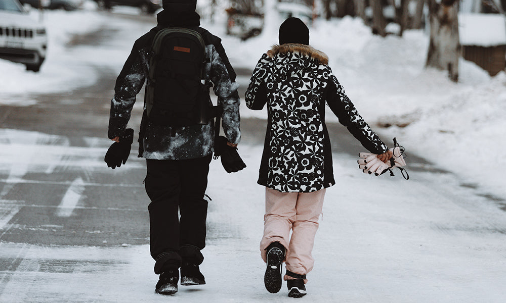 Two people walking in snow boots through a ski village