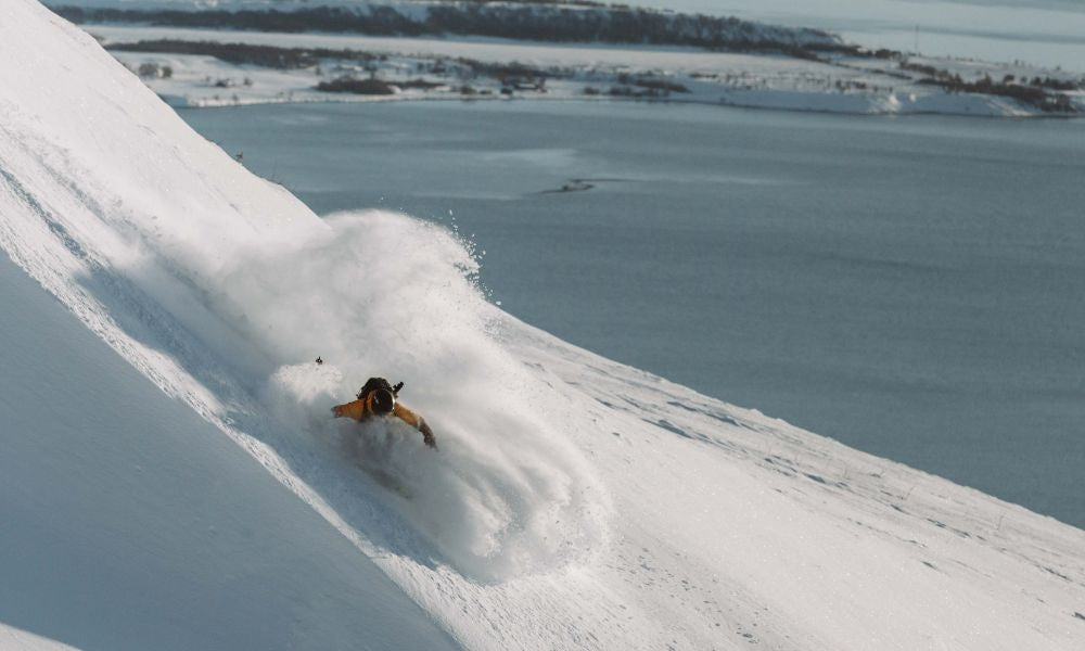 Skier skiing down a cornice mid pow turn 