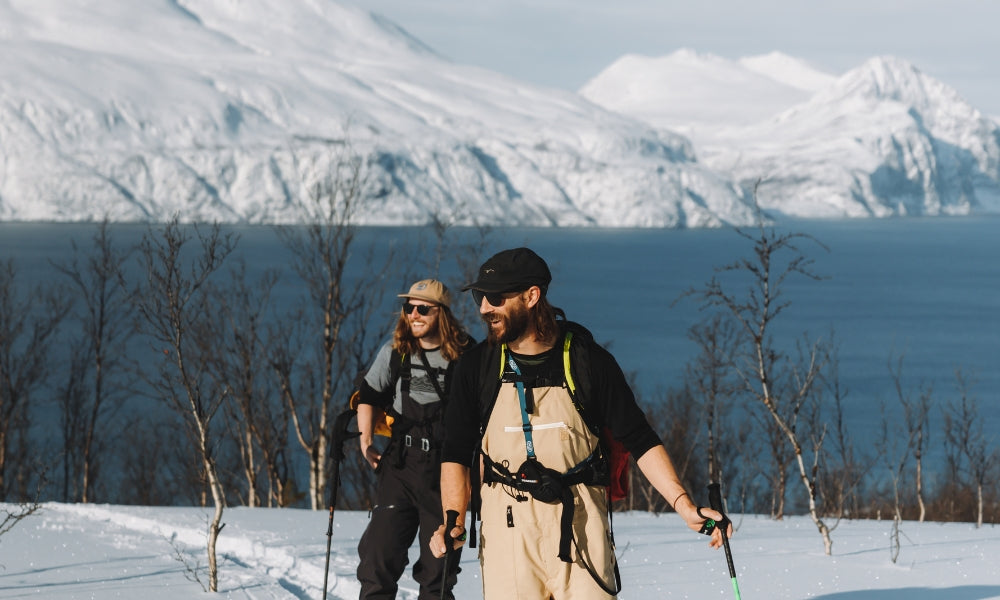 Two skiers smiling while touring with fjords and mountains behind them