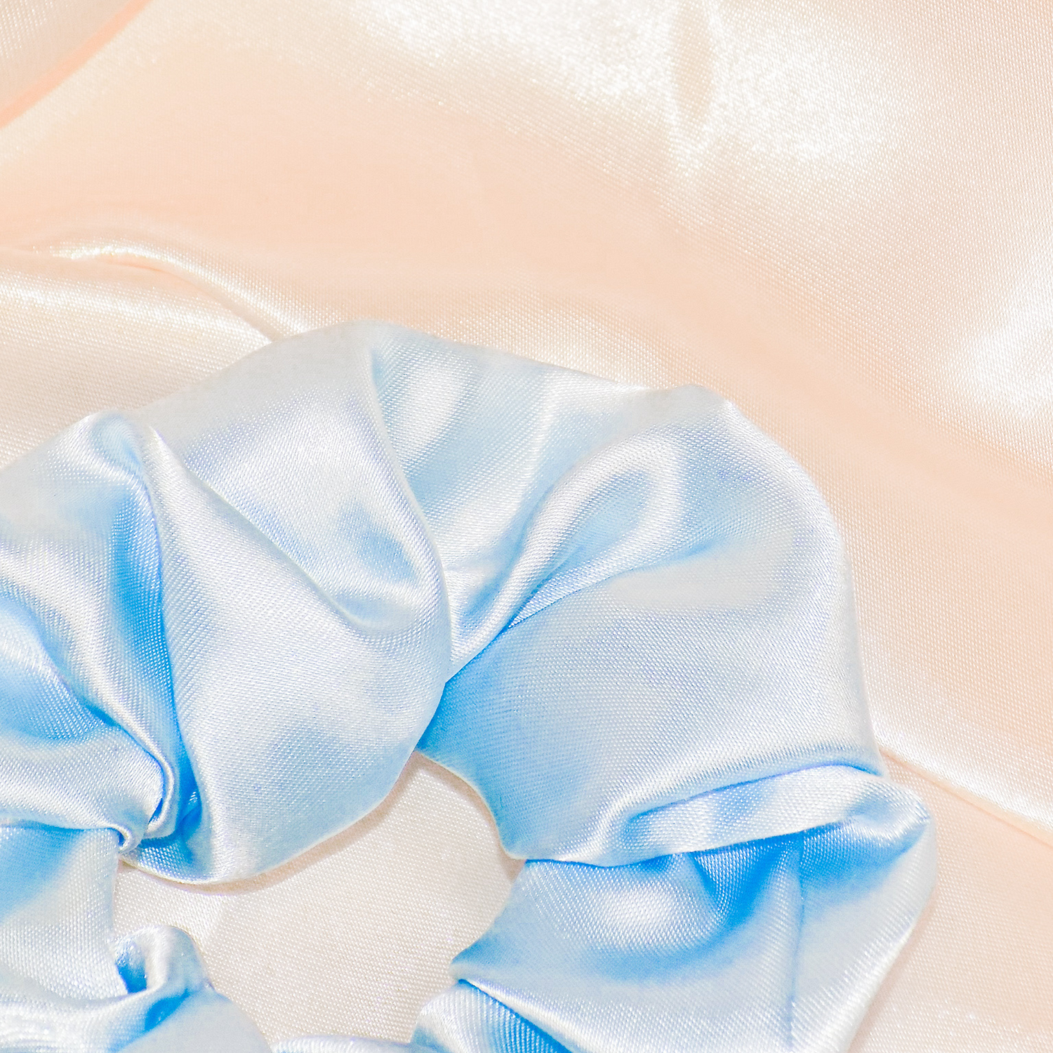 Light sky blue Satin Scrunchies in a glass bowl. The bowl is placed on Satin Silk materials.
