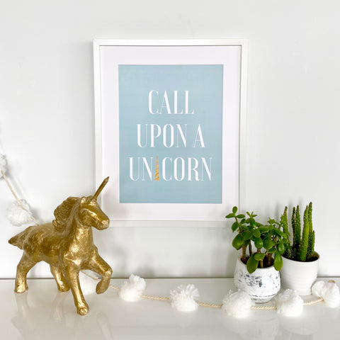 Framed Call Upon A Unicorn print in blue with golden unicorn and decorations in a nursery