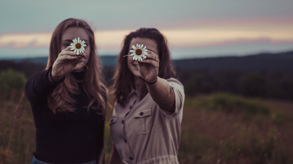 Zwei Freundinnen halten Blumen