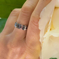 Flower band worry ring on a woman's hand next to a white flower