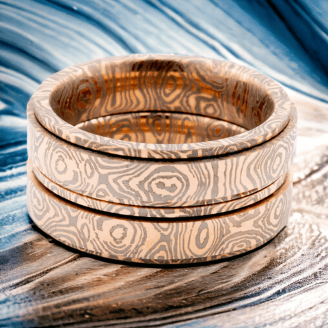 Two Damascus steel rings on golden abstract background