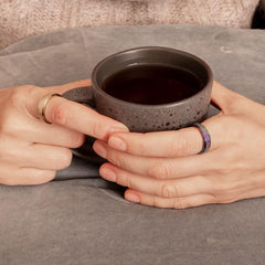 Woman's hands wearing meditation rings holding a mug