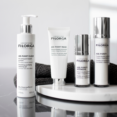 Filorga Age-Purify Clean, Mask, Intesnsive, and Fluid standing up on marble counter