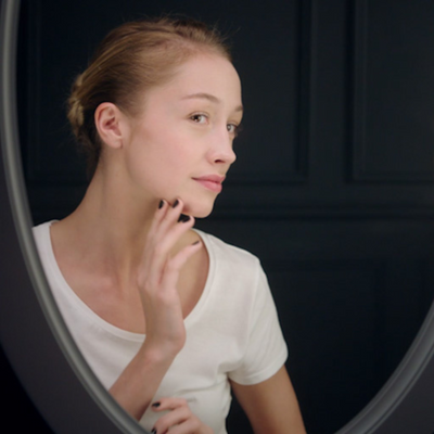 woman looking at her face in a mirror 