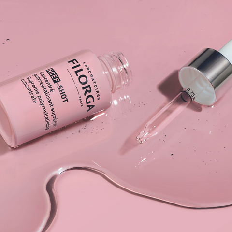 FILORGA NCEF-SHOT spilled around open bottle and dropper on pink background