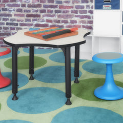 clover shaped school desk next to blue and red wobble stools in a classroom