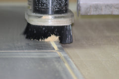 Closeup of CNC Machine cutting wood for tabletops, with saw dust