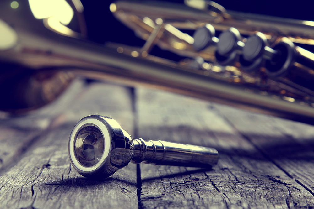 Trumpet mouthpiece on an old wooden table. Vintage style.