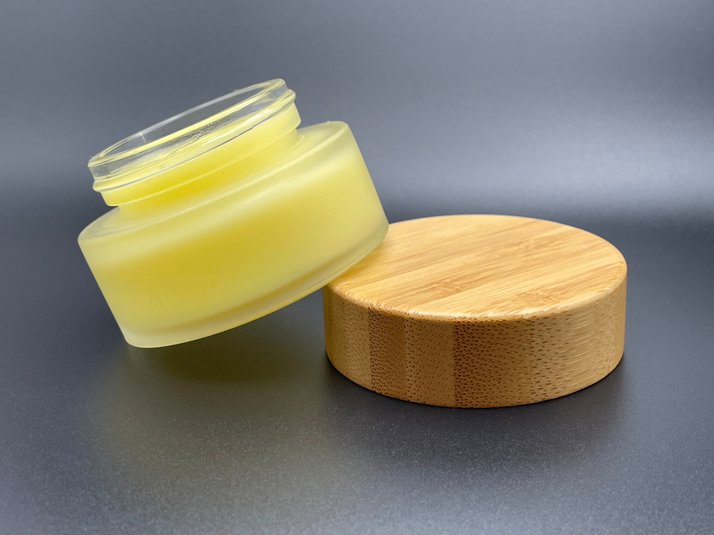 Sustainable cosmetic beeswax moisturizing hand cream in a in beautiful, sustainable packaging. The hand cream comes in a recyclable frosted glass jar with an aesthetic bamboo lid.