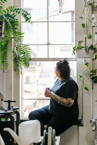 Esther Weinberg holding a glass staring out the window of her Melbourne work shop