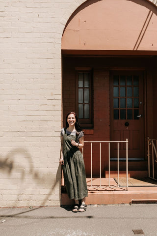 Julia Hogarth in a green dress standing under an archway by the street