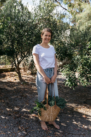 Kate Shore standing in the garden with a basket full of leafy vegetables