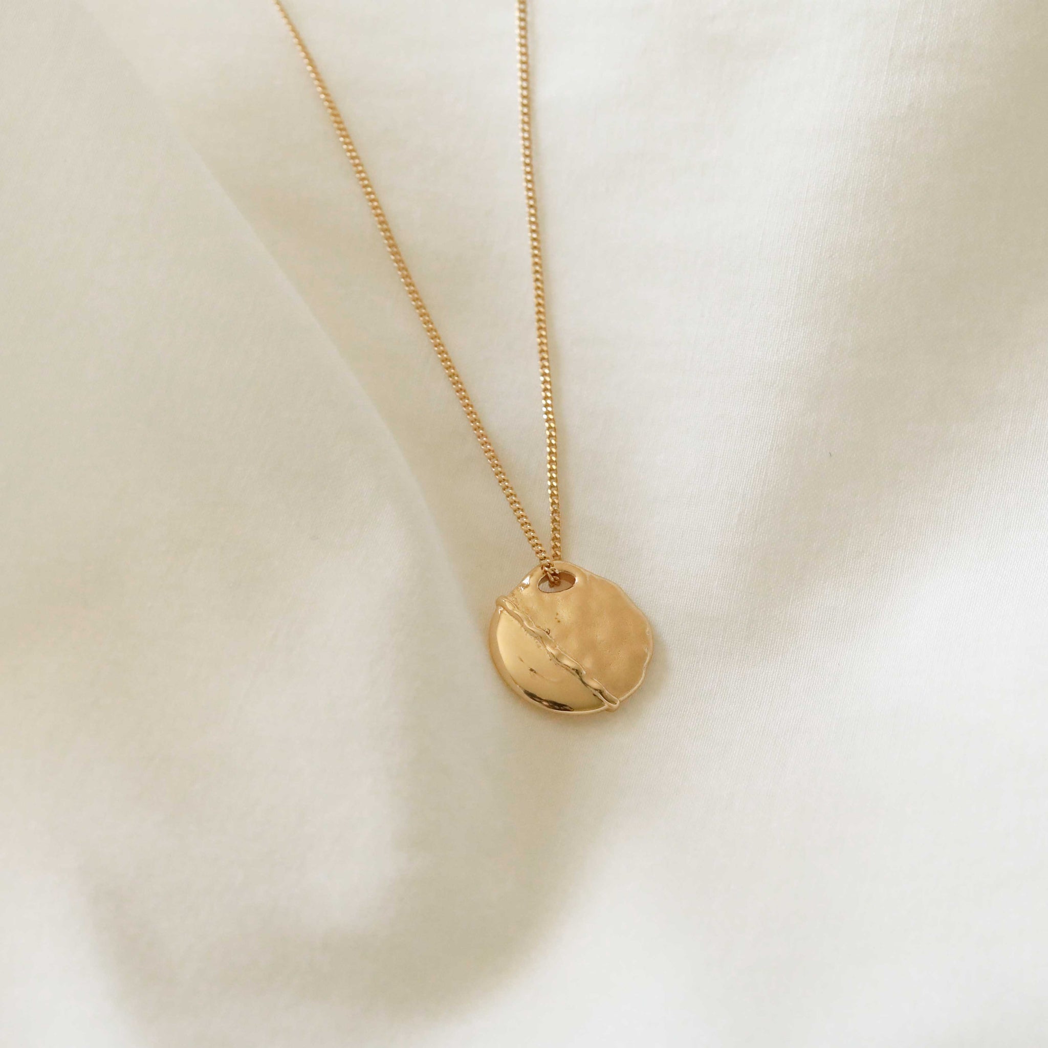 Flat lay shot of Molten Coin Pendant Necklace in Gold