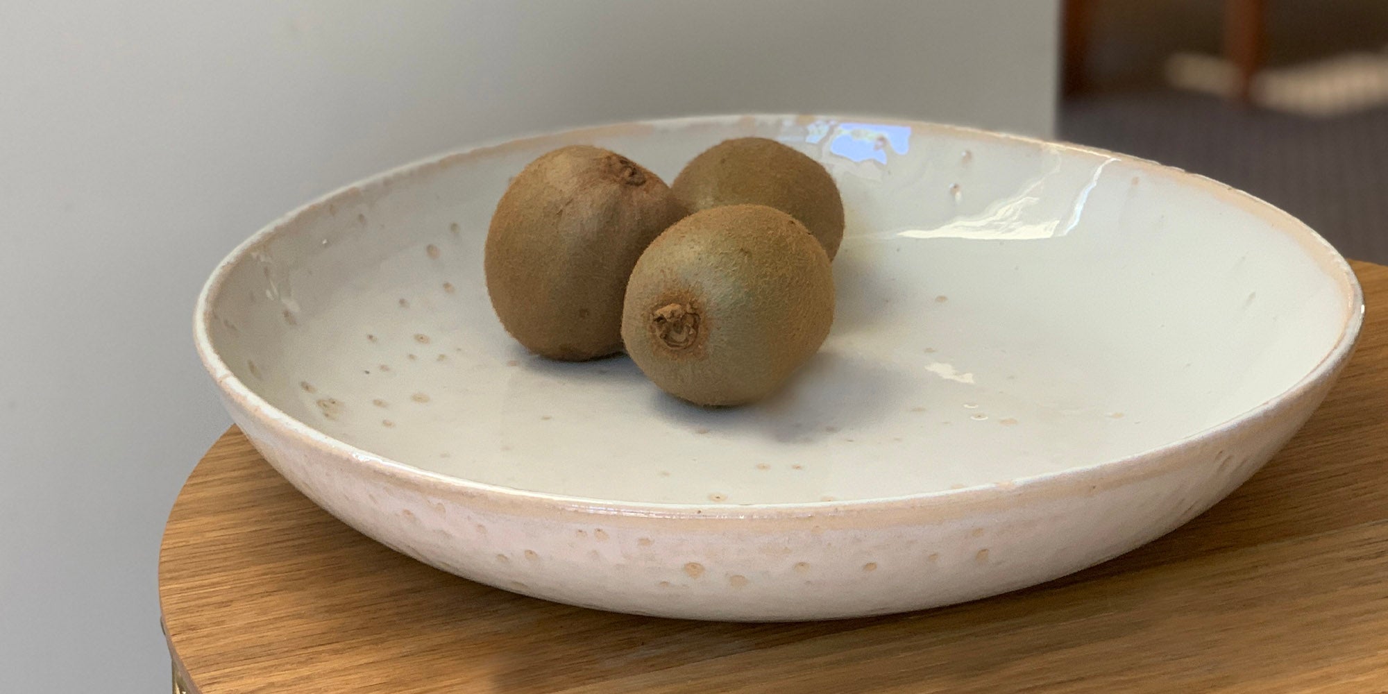 photo of a cream coloured bowl with three kiwi fruit in it