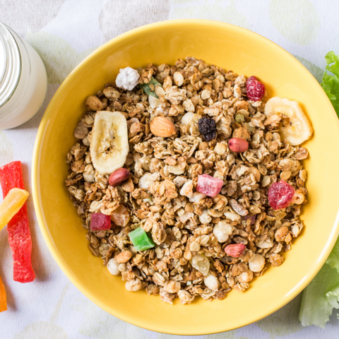 A dish of muesli cereal, fresh fruit slices such bananas, strawberries, and blueberries, drizzled honey, and sliced almonds served as a nutritious breakfast.