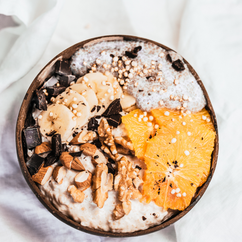 a bowl of baked oats with chocolate chips and almond slices on top. The almonds and chocolate chips are dispersed on top in a decorative pattern, and the oatmeal has a light brown colour with a creamy consistency.
