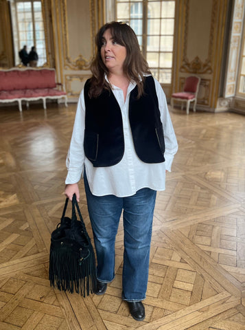 Femme grande taille portant un jean, une chemise blanche et un gilet sans manche en velours noir et sequins