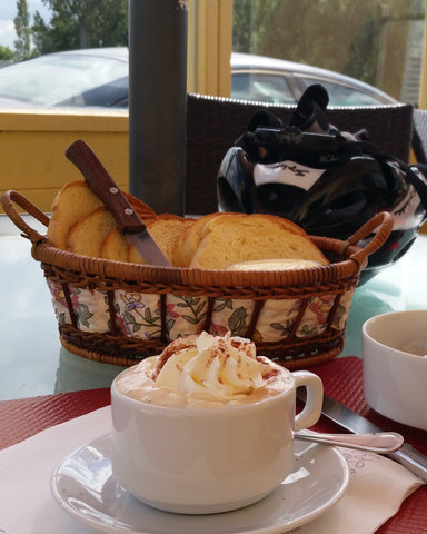 belgian cappucino with whipped cream and brioche basket behind