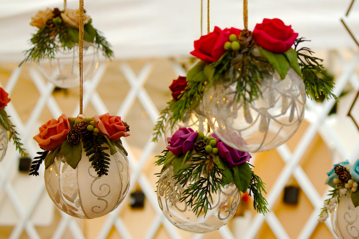Decorative clear glass baubles adorned with vibrant blooms and greenery, suspended as part of a festive event decoration.