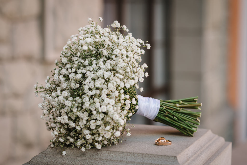 A large bouquet of baby’s breath flowers on a stone pillar.