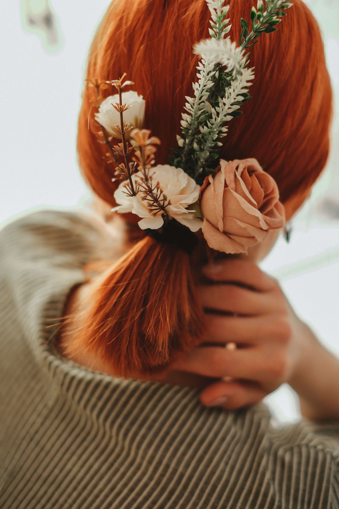 The bride dons a chic ponytail accented with striking flowers for her wedding day.