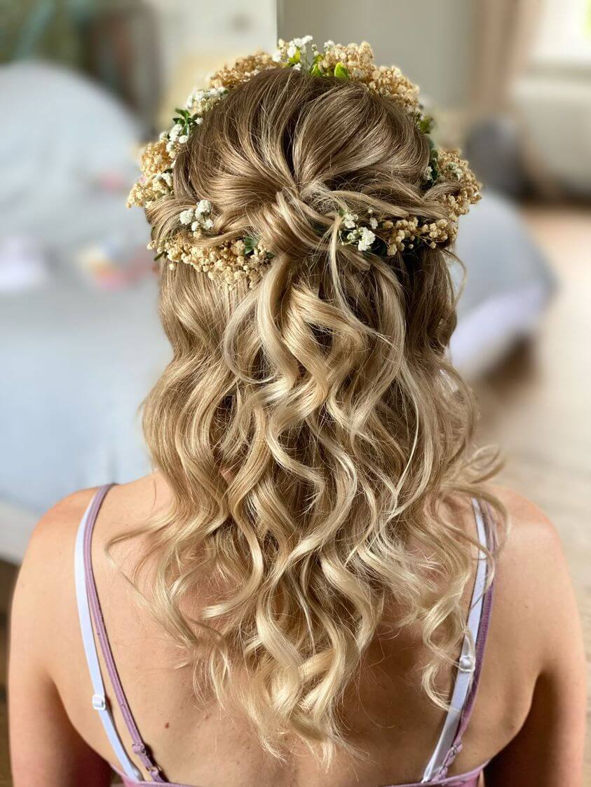 Bride wears flowers in her hair with cascading curls adorned with gypsophila.