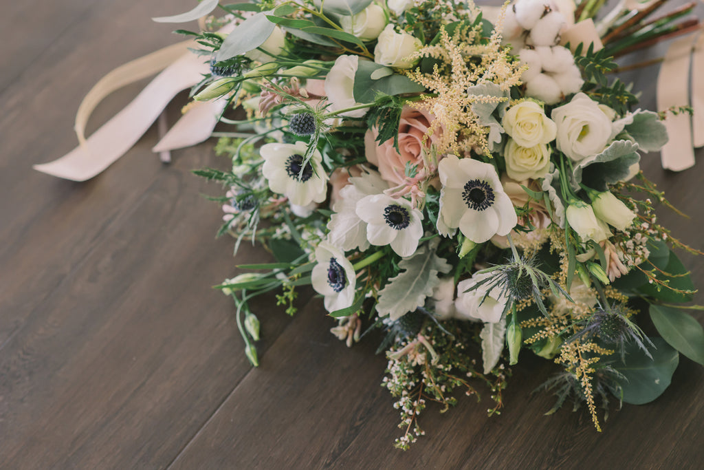 A wedding bouquet of white anemones and green foliage.