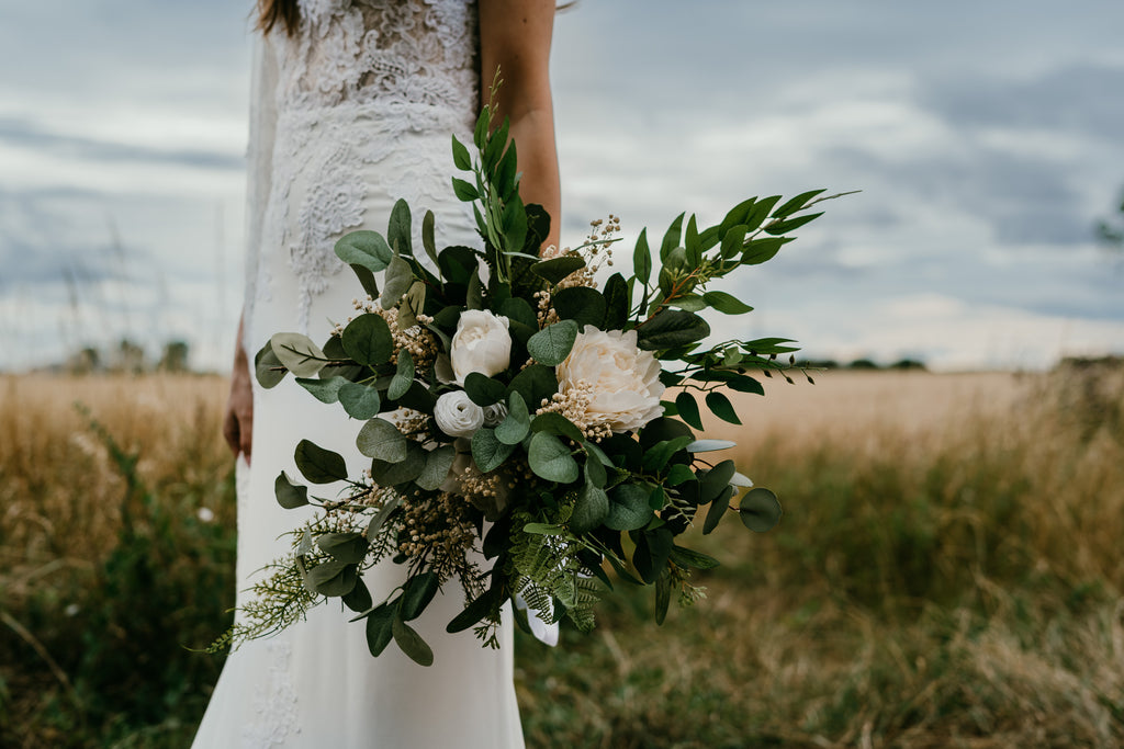 A bride holds a large dried flower bouquet full of green foliage by Hidden Botanics.