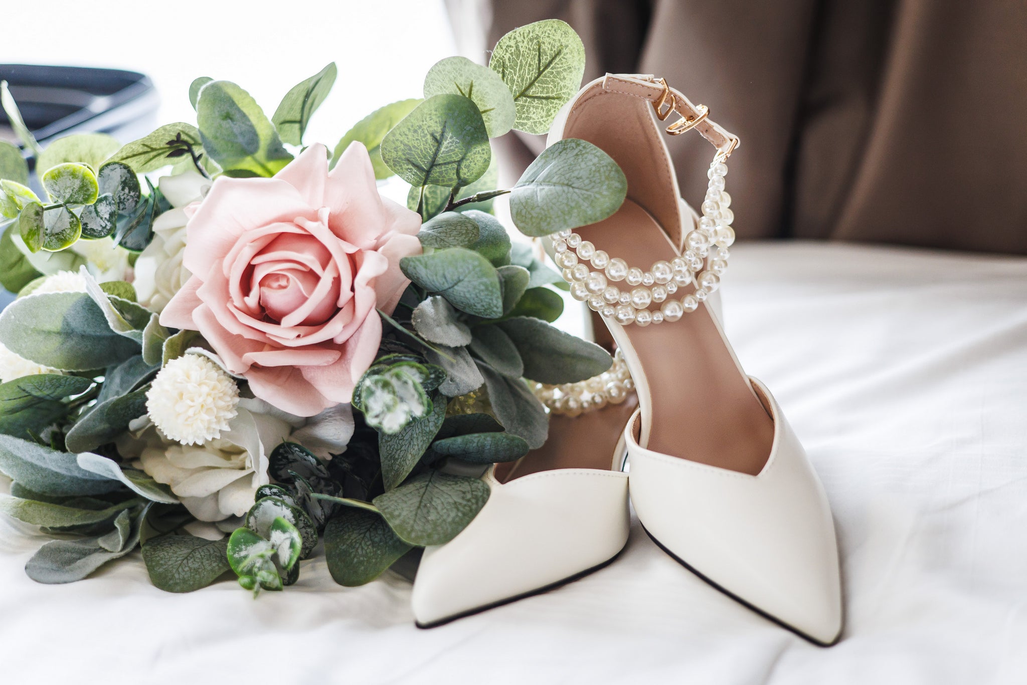 Cream bridal heels with pearl embellishments beside a pastel bouquet by Hidden Botanics.