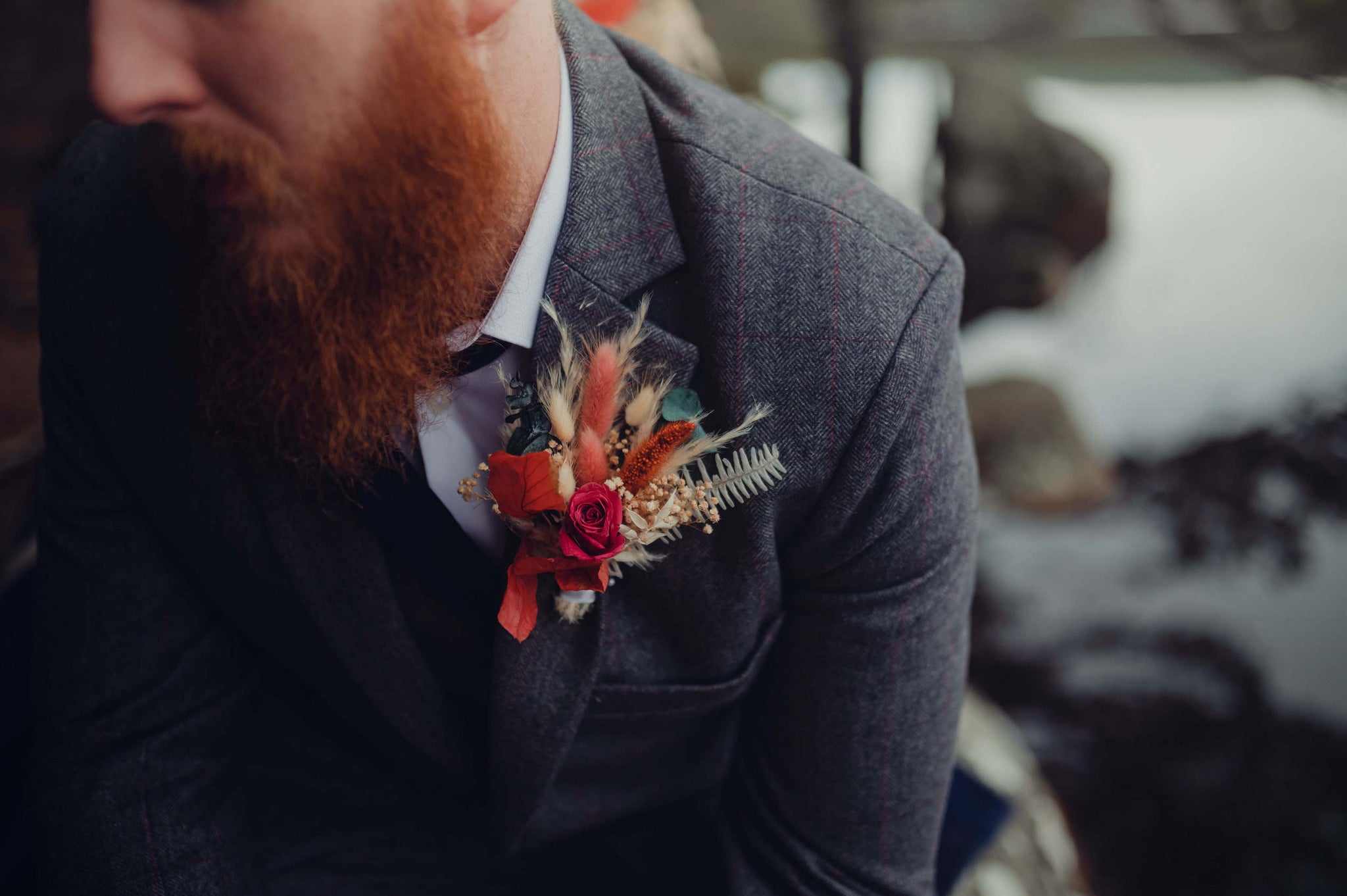 Groom wears Hidden Botanics red rose and dried wildflower buttonhole for wedding.