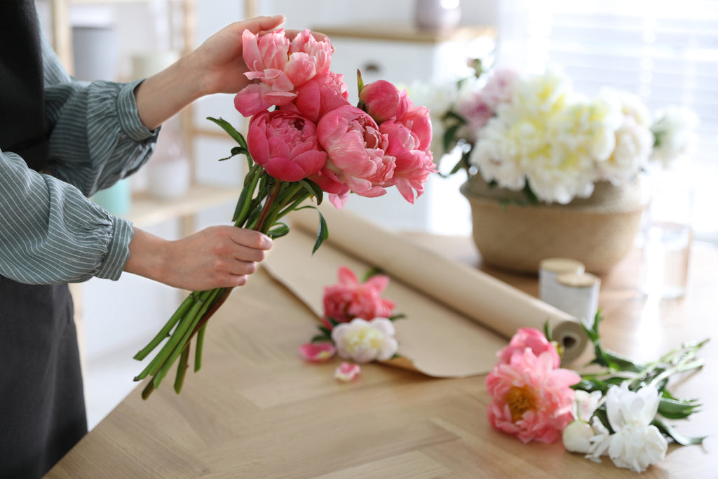 A person holding a bunch of pink peonies.