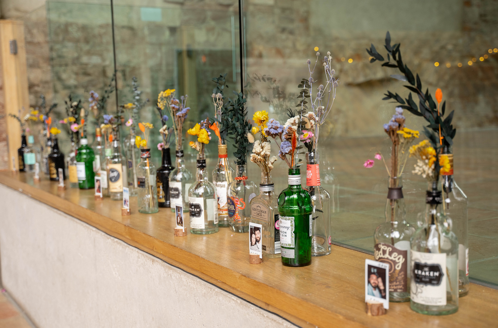Glass bottles line a windowsill holding dried floral arrangements from Hidden Botanics.