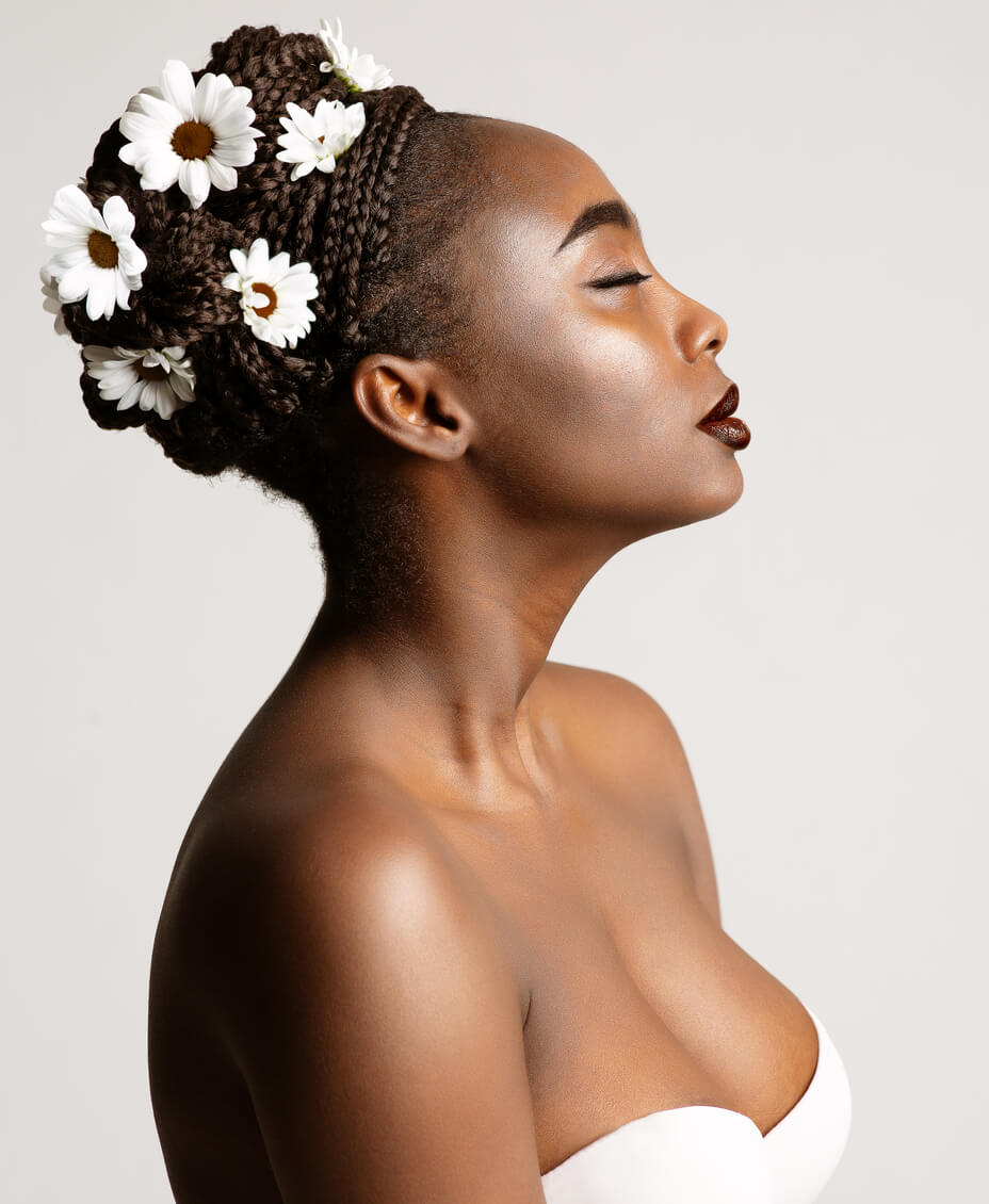 A braided bun bridal hairstyle embellished with daisies.