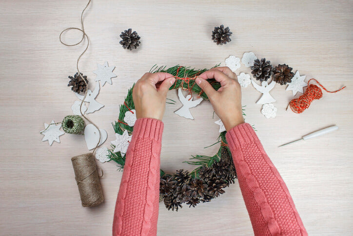 Woman adding personal touches to a Christmas wreath.
