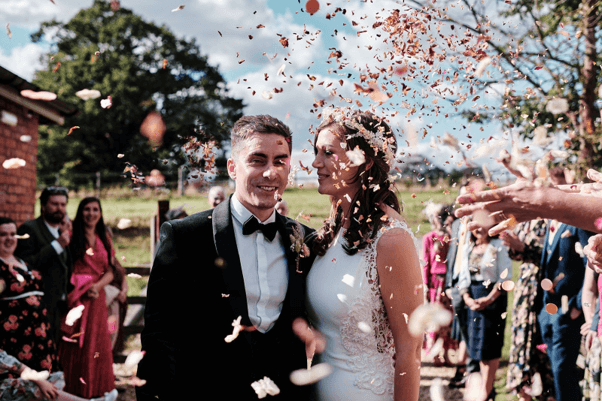 The joyful moment of a bride and groom being showered with petal confetti.