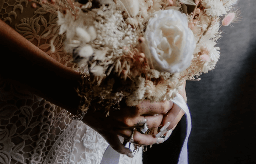 A close-up of a bride's hands showcasing a stunning wedding bouquet by Hidden Botanics.