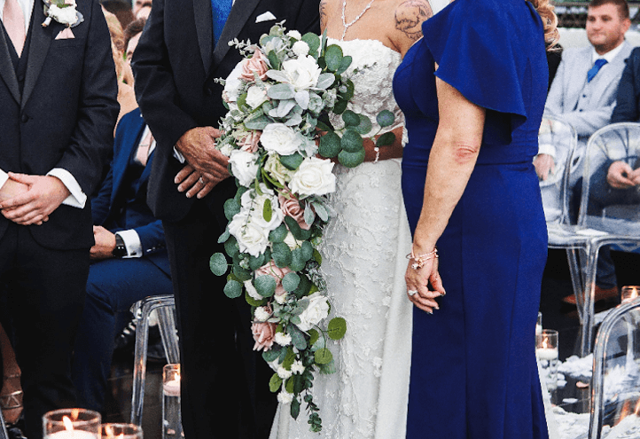 A bride at the altar with her parents holding a dramatic cascading wedding bouquet.