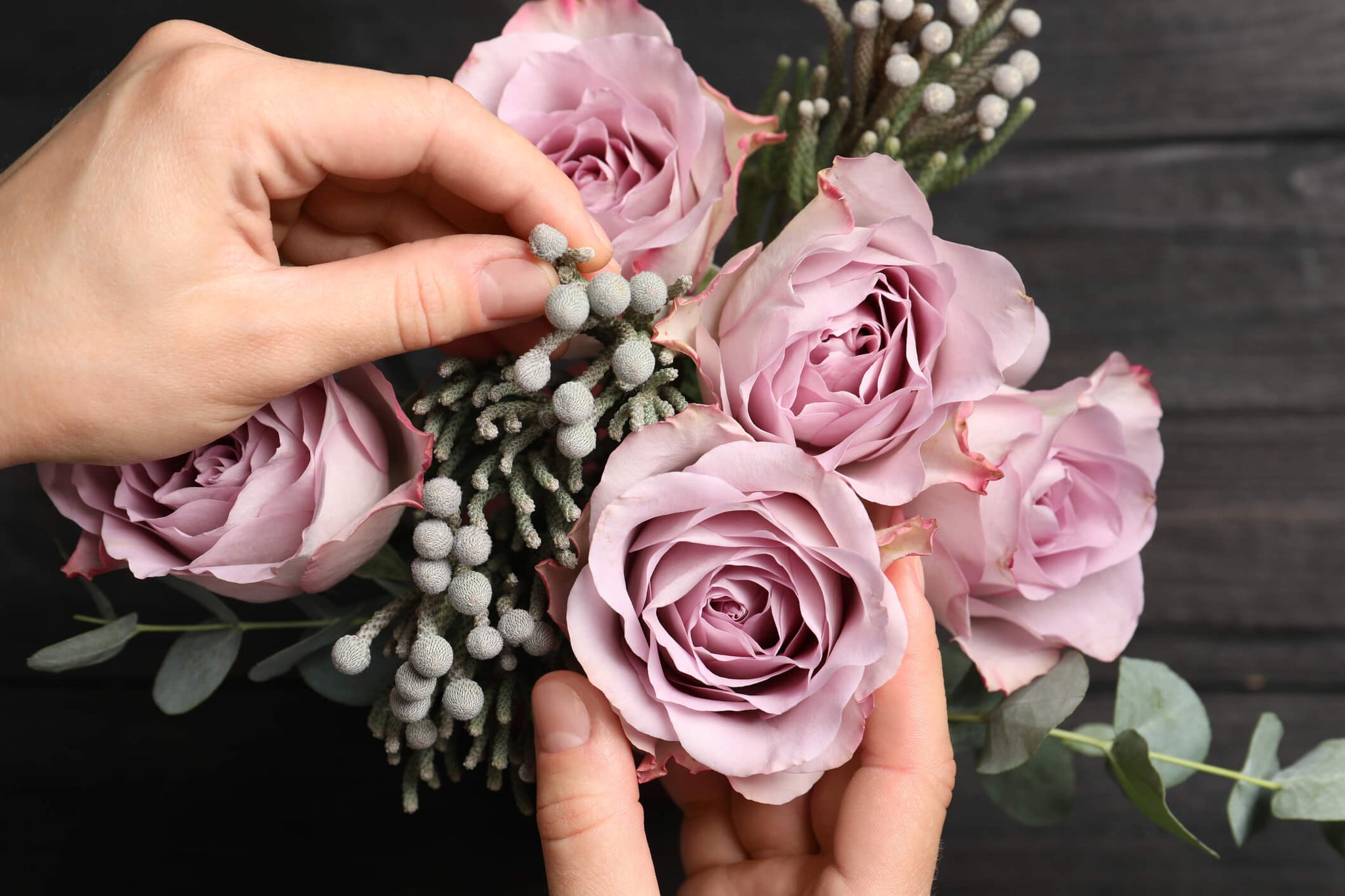 A person adding smaller flowers to a wedding bouquet.