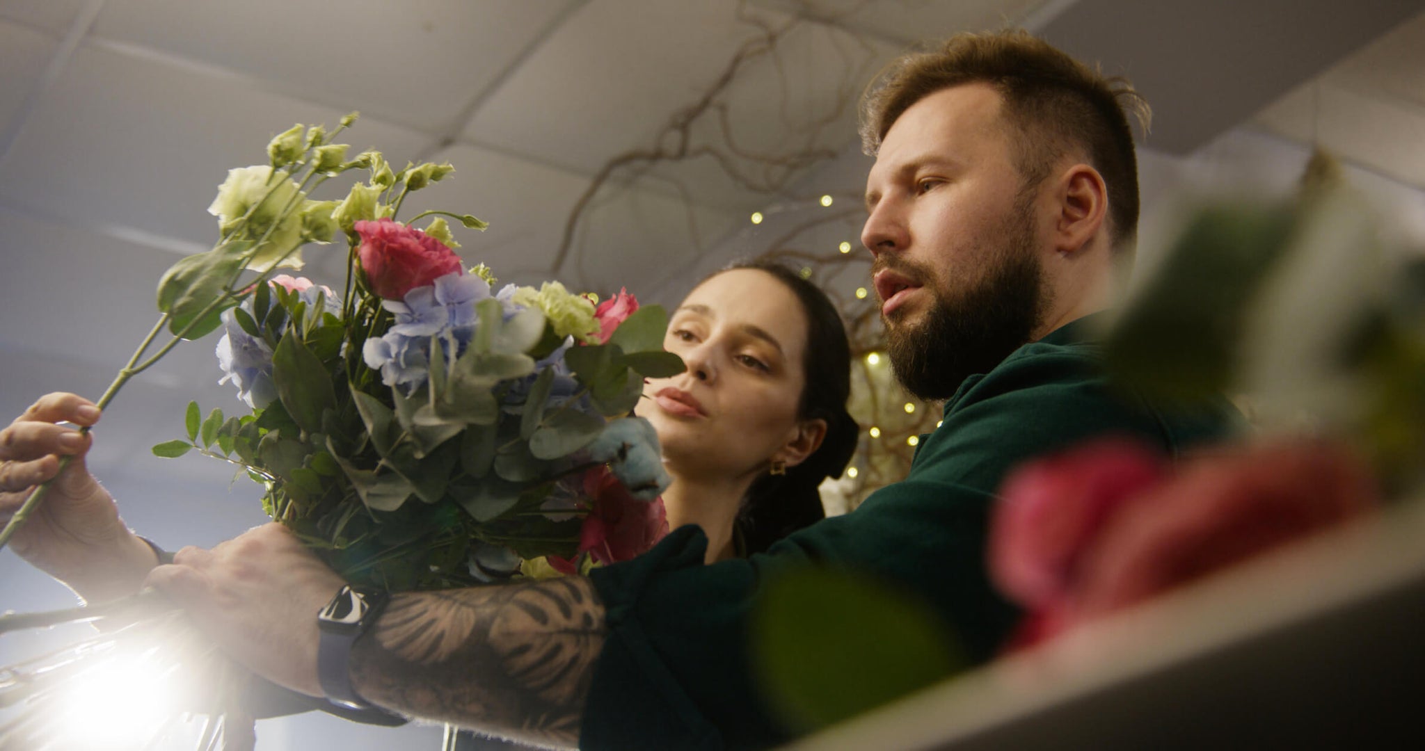 Two florists checking balance and adding flowers to a wedding bouquet.