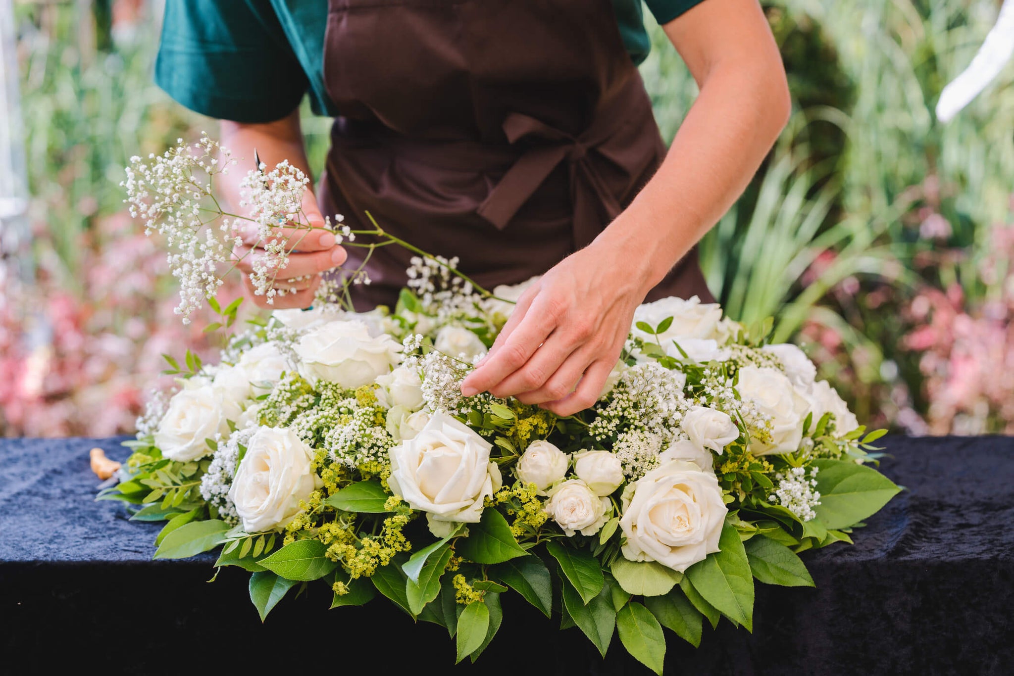 A person arranging a bridal bouquet holding a baby's breath.
