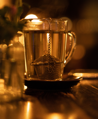 a tea strainer of chamomile tea steeping in a cup of hot water