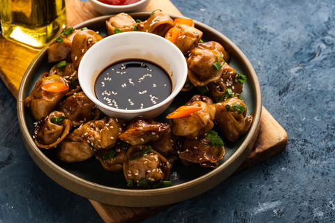 A plate of dumplings with soy sauce