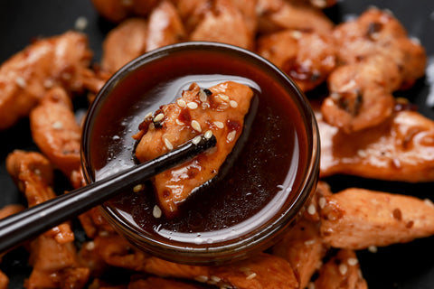 Chicken being dipped in teriyaki sauce